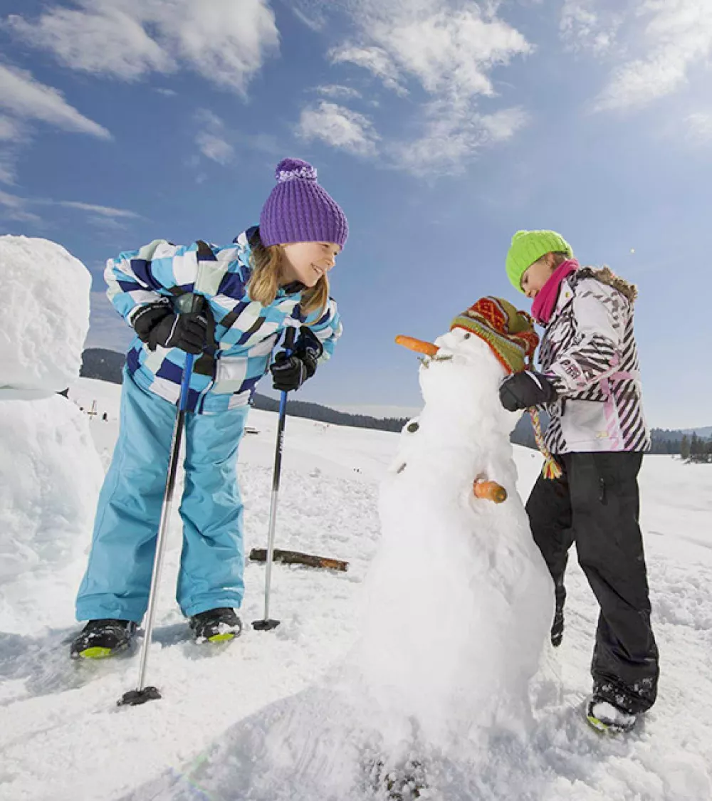 Spaß im Schnee beim Schneemannbauen Familienzeit im Winterurlaub